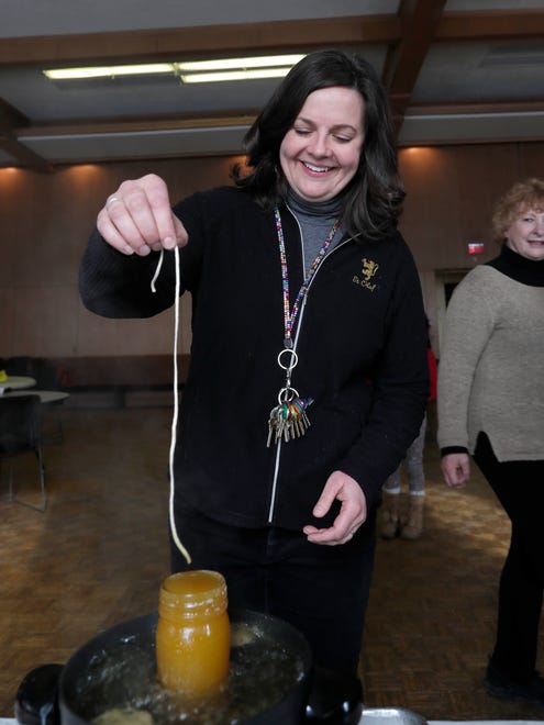 Pastor Lisa Bates-Froiland dips a wick to start a new beeswax candle at Redeemer Lutheran Church.
