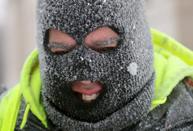 Robert Delgado smiles through his snow-covered ski mask while shoveling in front of the Milwaukee Public Library on W. Wisconsin Avenue at N. 8th Street in Milwaukee.