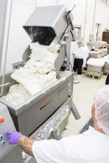 Employee Lizette Regalado watches as a buggy of Chevre is dumped into the mixer where salt and flavorings will be added prior to extrusion and packaging.