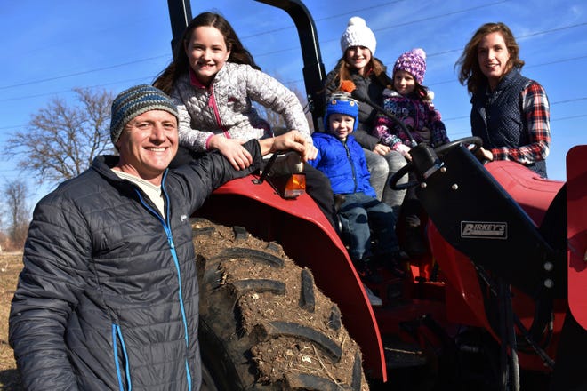 In this Dec. 21, 2019, photo, Adam Aberle, from left to right, Ava Aberle, Andrew Aberle, Kaylee Aberle and wife Kristina gather for a family photo on a tractor in Beloit, Wis. The family is farming hemp together.