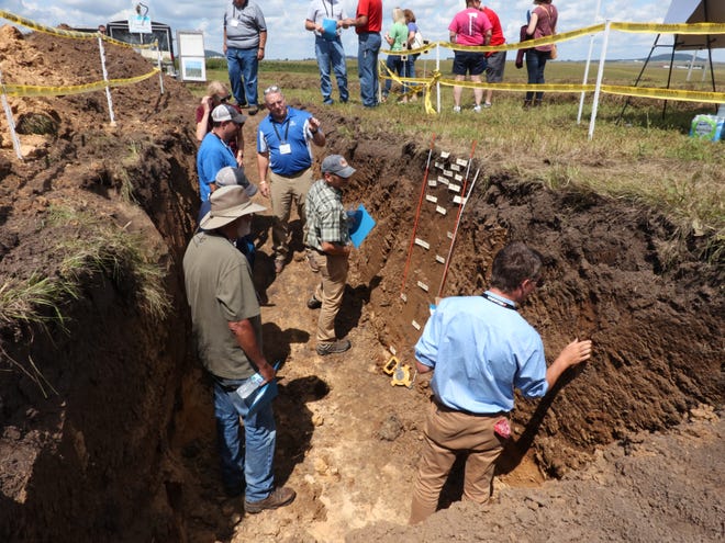 Participants at a field day with the Lafayette Ag Stewardship Alliance learn about how water penetrates soil pits, August 2019.