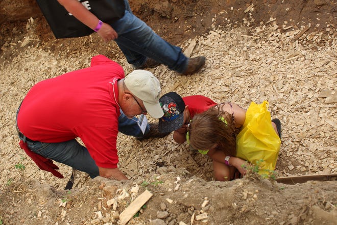 Jim Barnes of NRCS shows young guests the composition of soil in the soil pit at Farm Technology Days in Clark County, July 12-14, 2022.